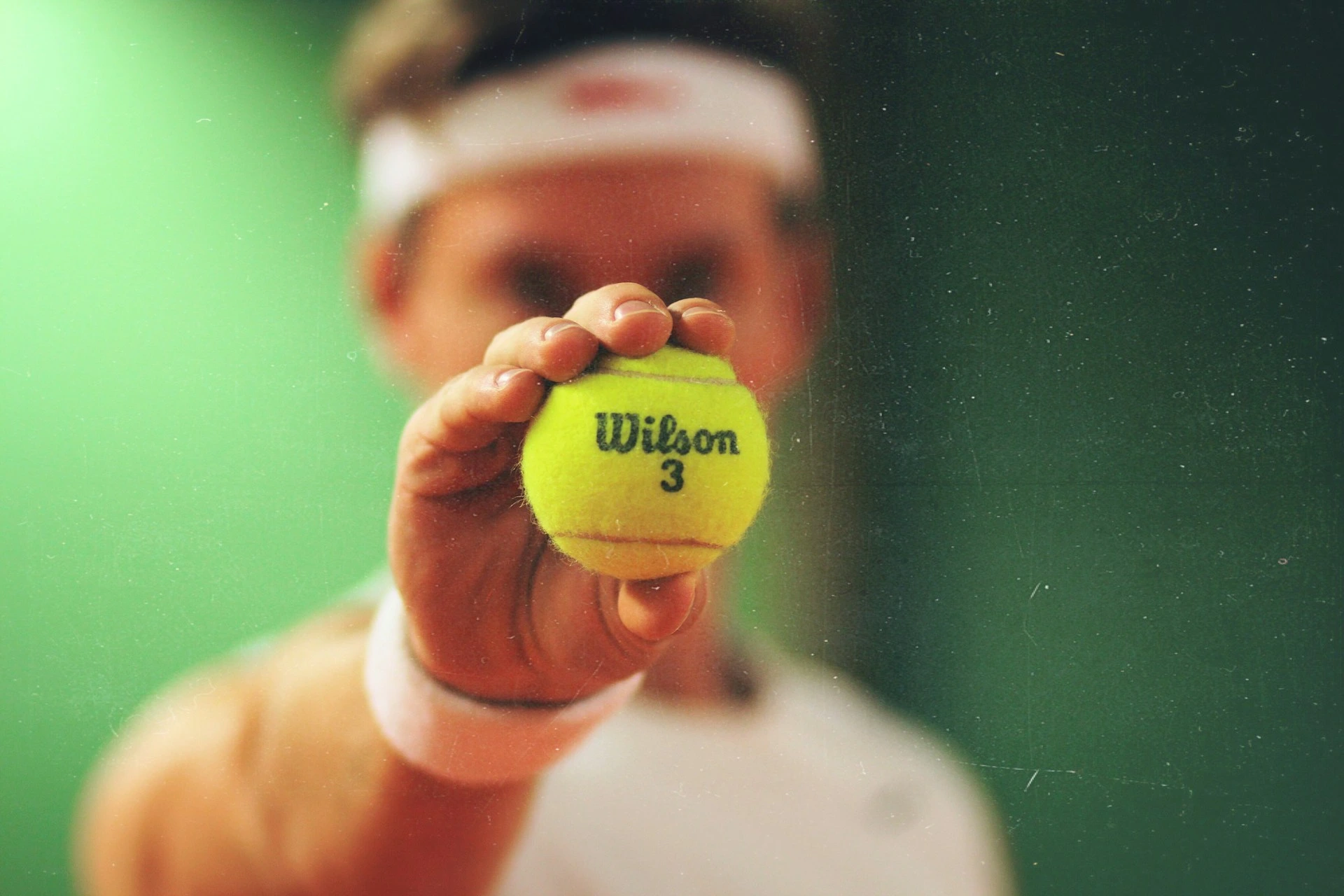 Joueur de tennis montrant une balle jaune Wilson